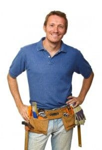 Smiling handyman in blue polo wearing a tool belt with tools, hands on hips, white background