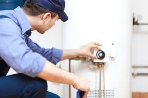 Technician repairing a residential water heater, adjusting the temperature valve